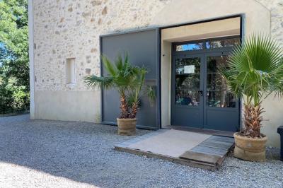 Terrasse aménagée pour un événement avec tables hautes drapées de noir, guirlandes lumineuses et végétation en arrière-plan.