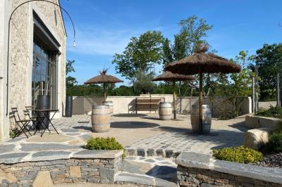 Terrasse aménagée pour un événement avec tables hautes drapées de noir, guirlandes lumineuses et végétation en arrière-plan.