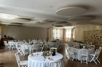 Terrasse aménagée pour un événement avec tables hautes drapées de noir, guirlandes lumineuses et végétation en arrière-plan.