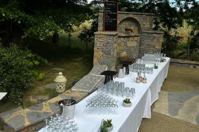 Terrasse aménagée pour un événement avec tables hautes drapées de noir, guirlandes lumineuses et végétation en arrière-plan.