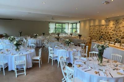 Tables en tonneaux et tabourets blancs disposés en plein air sous des arbres dans un cadre naturel et ombragé.