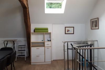 Salle de réunion avec tables noires, chaises, écran de projection, tableau blanc et éclairage naturel.