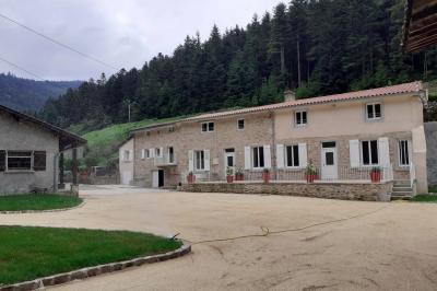 Cuisine professionnelle avec plans de travail en inox, réfrigérateur blanc, étagères murales et sol en carrelage.