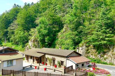 Cuisine professionnelle avec plans de travail en inox, réfrigérateur blanc, étagères murales et sol en carrelage.