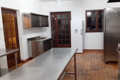 Cuisine professionnelle avec plans de travail en inox, réfrigérateur blanc, étagères murales et sol en carrelage.