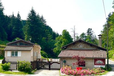 Cuisine professionnelle avec plans de travail en inox, réfrigérateur blanc, étagères murales et sol en carrelage.