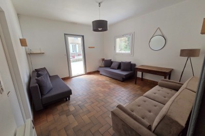 Salle de bain moderne avec douche à l'italienne, paroi vitrée, meuble vasque blanc et carrelage beige et marron.
