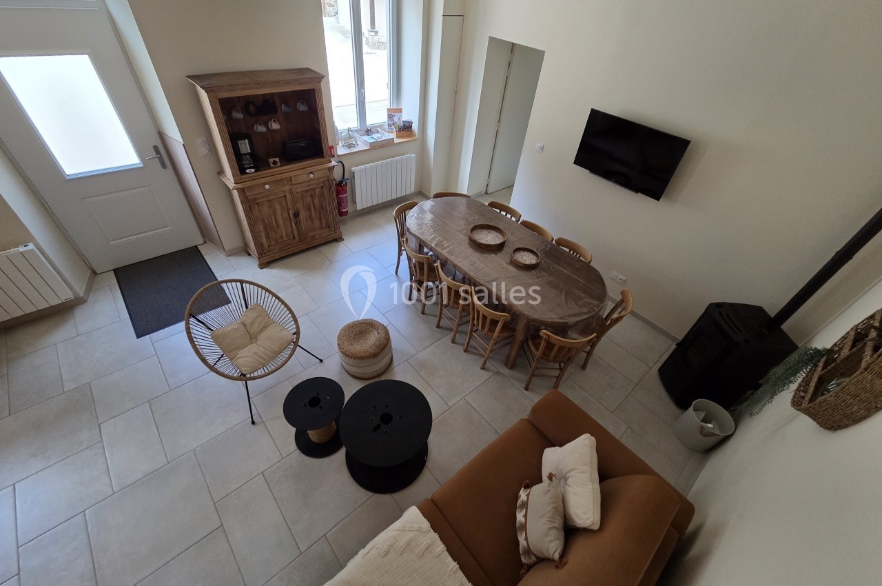 Vue d'une pièce de vie lumineuse avec table à manger, canapé, poêle à bois et mobilier en bois clair.