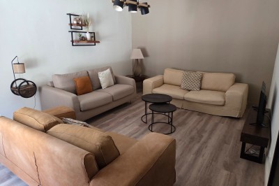 Salle de bain moderne avec douche à l'italienne, paroi vitrée, meuble vasque blanc et carrelage beige et marron.