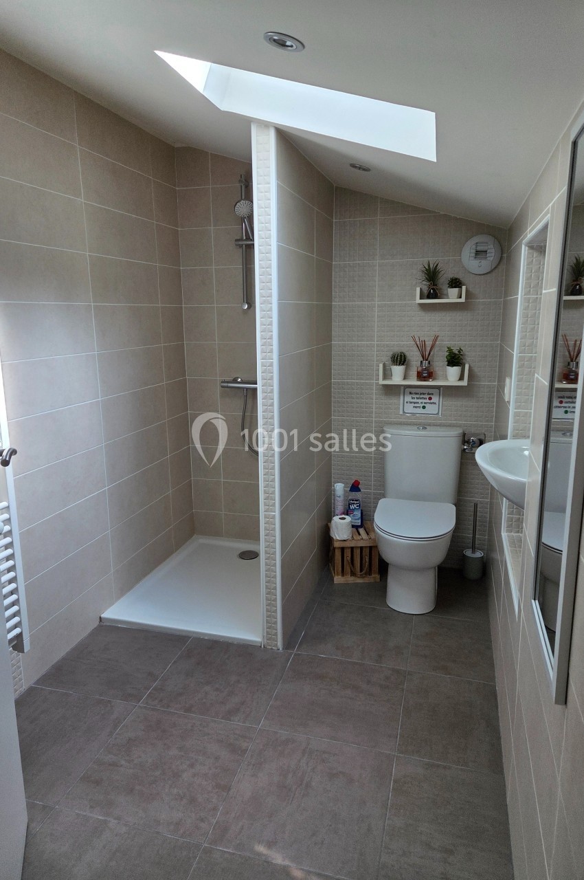 Salle de bain moderne avec douche à l'italienne, toilettes, lavabo, étagères murales et lumière naturelle.