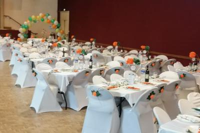 Serviettes pliées en forme de fleurs, orange et bleue, disposées sur des verres transparents sur une table en bois.