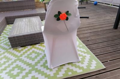 Serviettes pliées en forme de fleurs, orange et bleue, disposées sur des verres transparents sur une table en bois.