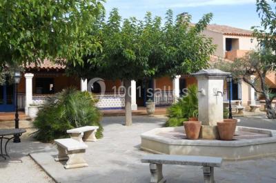 Une cavalière en tenue traditionnelle guide un cheval blanc dans une arène devant un public attentif.