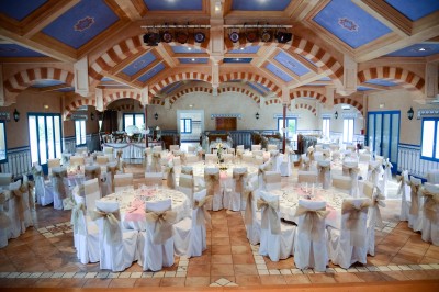 Une cavalière en tenue traditionnelle guide un cheval blanc dans une arène devant un public attentif.