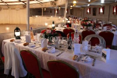 Une cavalière en tenue traditionnelle guide un cheval blanc dans une arène devant un public attentif.