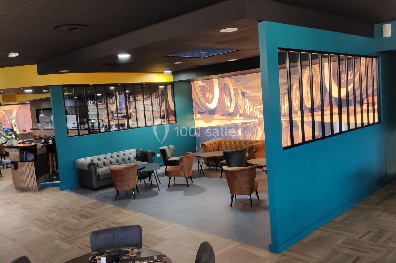 Espace intérieur moderne avec fauteuils, tables et cloisons vitrées, décoré de fresques représentant des tonneaux.