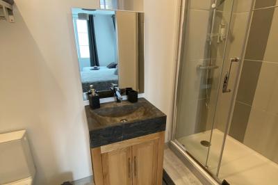 Bâtiment rural éclairé de nuit avec des murs en pierre, des fenêtres rouges et une entrée vitrée sur la droite.