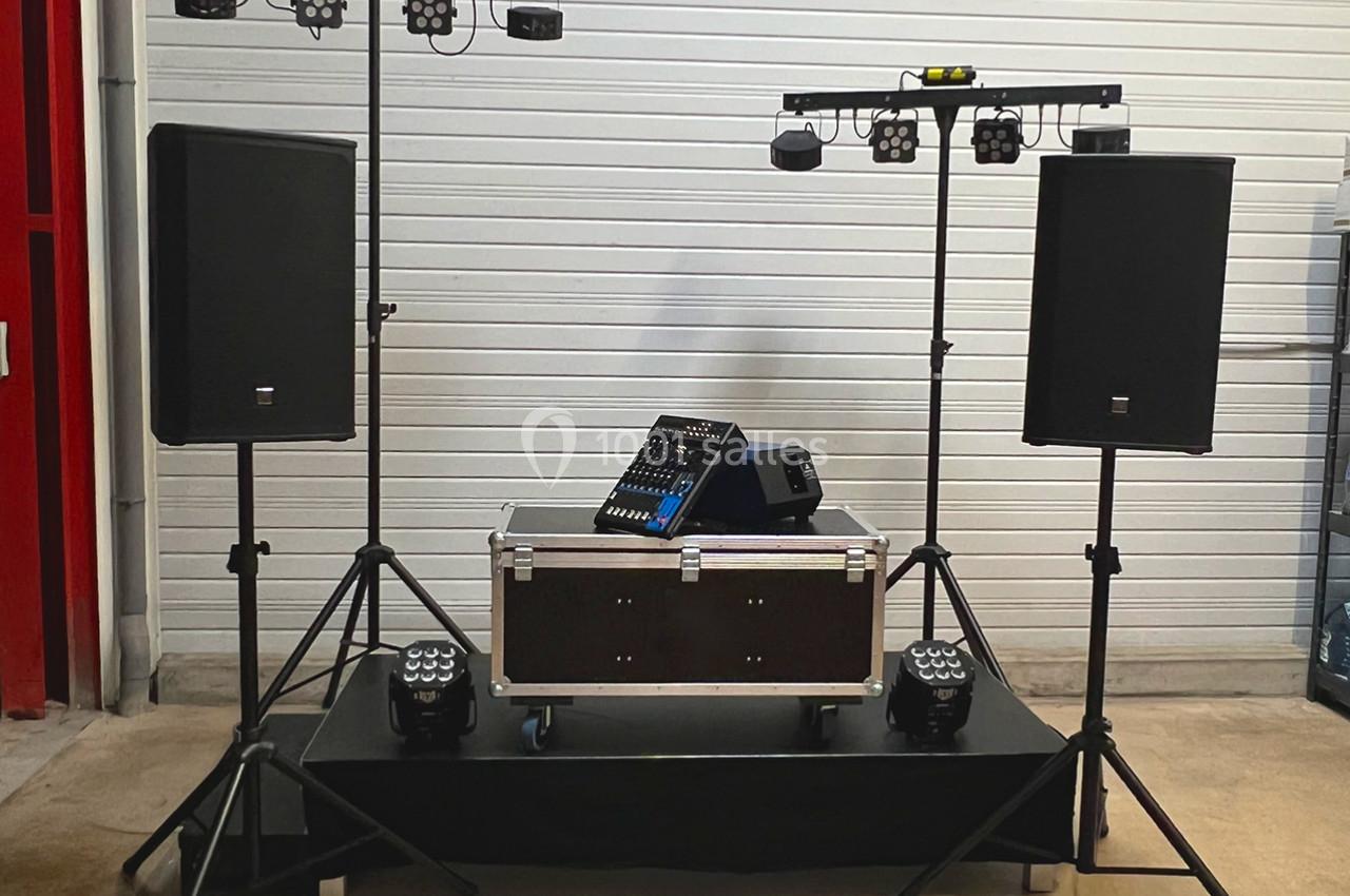 Équipement de sonorisation et d'éclairage installé sur une estrade dans un espace intérieur.