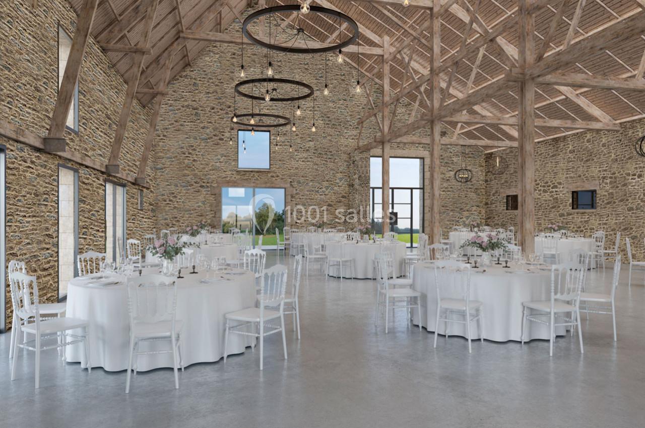 Salle de réception lumineuse avec murs en pierre, poutres apparentes et tables rondes dressées pour un événement.