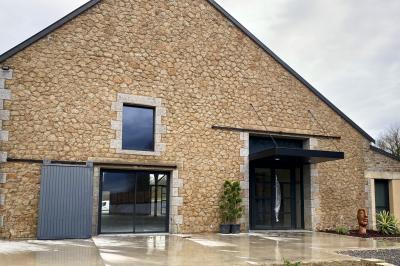 Échelle en bois décorée de bouteilles en verre marron, fleurs séchées et cadre sur fond de mur en pierre.