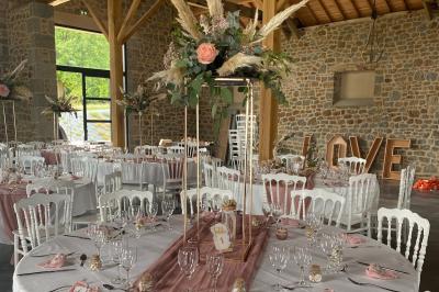 Échelle en bois décorée de bouteilles en verre marron, fleurs séchées et cadre sur fond de mur en pierre.