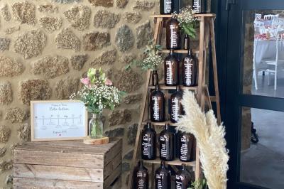 Échelle en bois décorée de bouteilles en verre marron, fleurs séchées et cadre sur fond de mur en pierre.