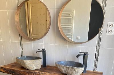 Échelle en bois décorée de bouteilles en verre marron, fleurs séchées et cadre sur fond de mur en pierre.