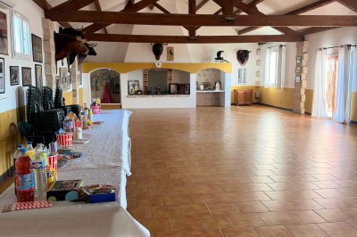 Abri extérieur avec toit en tuiles, tables et panneaux d'affichage, entouré de végétation et ciel dégagé.