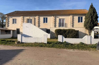 Abri extérieur avec toit en tuiles, tables et panneaux d'affichage, entouré de végétation et ciel dégagé.