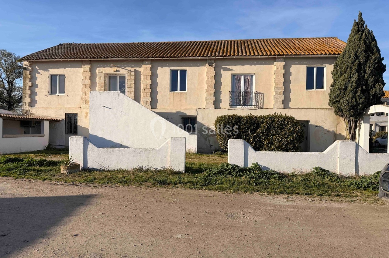 Grande maison de campagne à un étage avec façade beige, toit en tuiles et jardin clôturé devant.