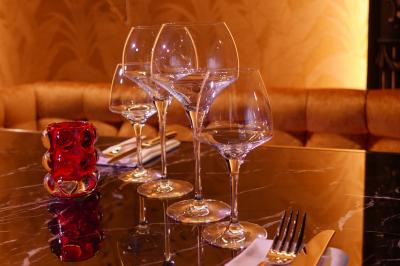 Quatre verres à vin alignés sur une table en marbre noir, avec un photophore rouge et des couverts à proximité.
