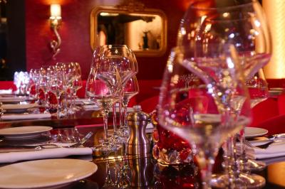 Quatre verres à vin alignés sur une table en marbre noir, avec un photophore rouge et des couverts à proximité.
