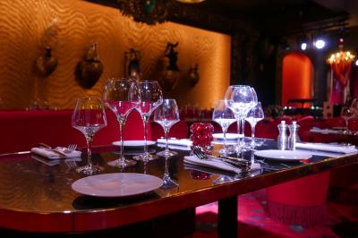 Quatre verres à vin alignés sur une table en marbre noir, avec un photophore rouge et des couverts à proximité.
