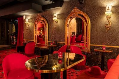 Quatre verres à vin alignés sur une table en marbre noir, avec un photophore rouge et des couverts à proximité.