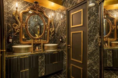 Quatre verres à vin alignés sur une table en marbre noir, avec un photophore rouge et des couverts à proximité.