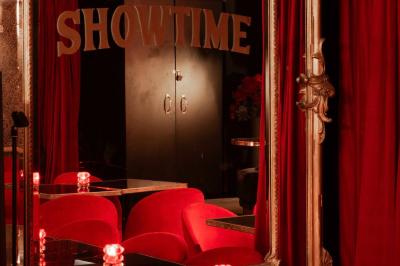 Quatre verres à vin alignés sur une table en marbre noir, avec un photophore rouge et des couverts à proximité.