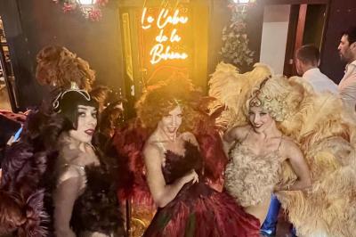 Quatre verres à vin alignés sur une table en marbre noir, avec un photophore rouge et des couverts à proximité.