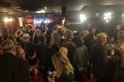 Quatre verres à vin alignés sur une table en marbre noir, avec un photophore rouge et des couverts à proximité.