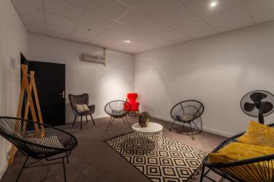 Salle de détente avec fauteuils variés, table basse, tapis géométrique et éclairage tamisé.