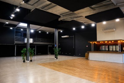 Miniature Location salle Pérols (Hérault) - Espace de l'Etang de l'Or #10 Vue intérieure d'une grande salle avec parquet, éclairage suspendu, balustrade métallique et murs noirs et blancs.