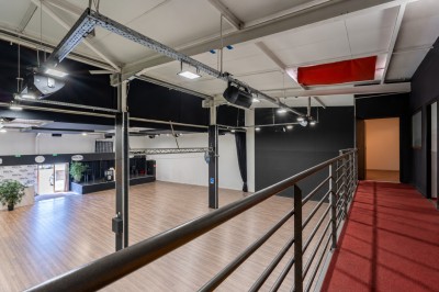 Miniature Location salle Pérols (Hérault) - Espace de l'Etang de l'Or #13 Vue intérieure d'une grande salle avec parquet, éclairage suspendu, balustrade métallique et murs noirs et blancs.