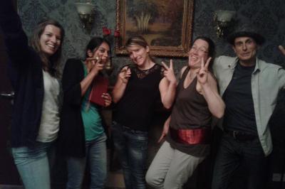 Deux femmes observent un élément lumineux dans un décor naturel avec des plantes et des rochers roses.