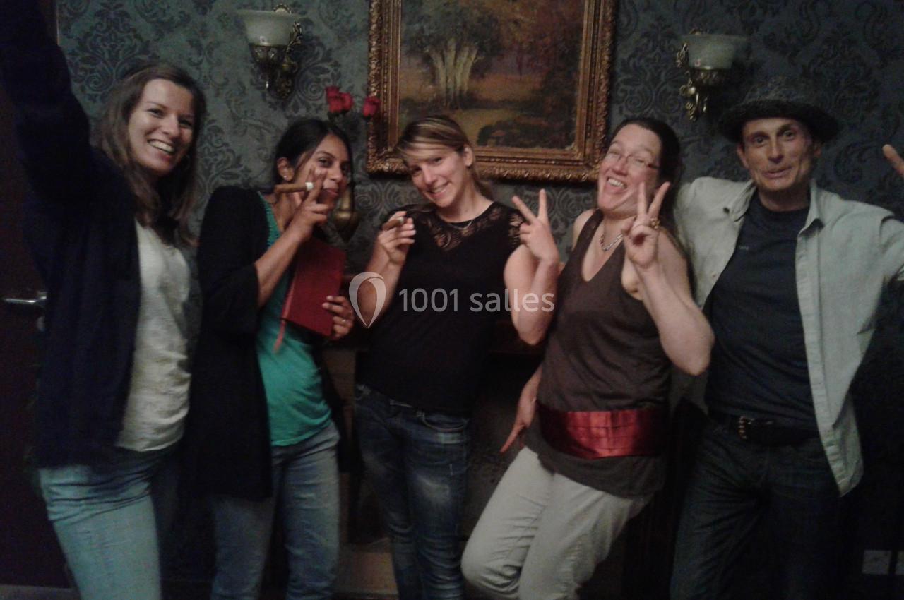 Cinq personnes souriantes posent devant un mur décoré avec un tableau et des appliques murales.