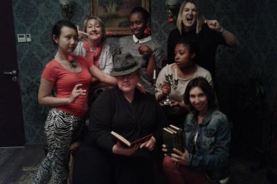 Deux femmes observent un élément lumineux dans un décor naturel avec des plantes et des rochers roses.