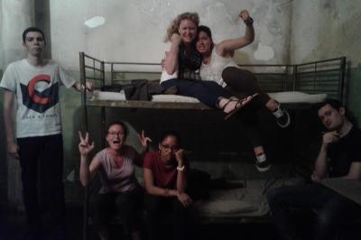 Deux femmes observent un élément lumineux dans un décor naturel avec des plantes et des rochers roses.