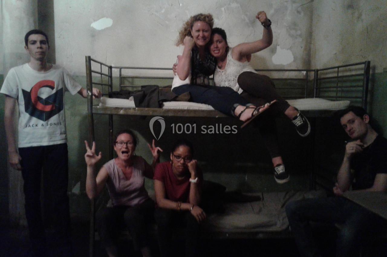 Un groupe de personnes pose dans une pièce avec des lits superposés et un mur à l'aspect vieilli.