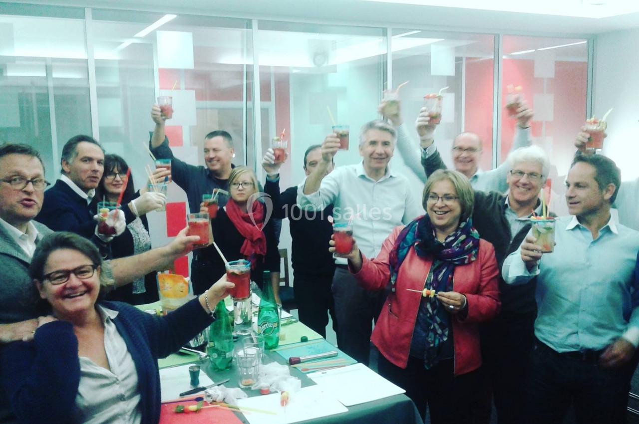 Un groupe de personnes souriantes trinque avec des boissons dans un cadre intérieur lumineux.
