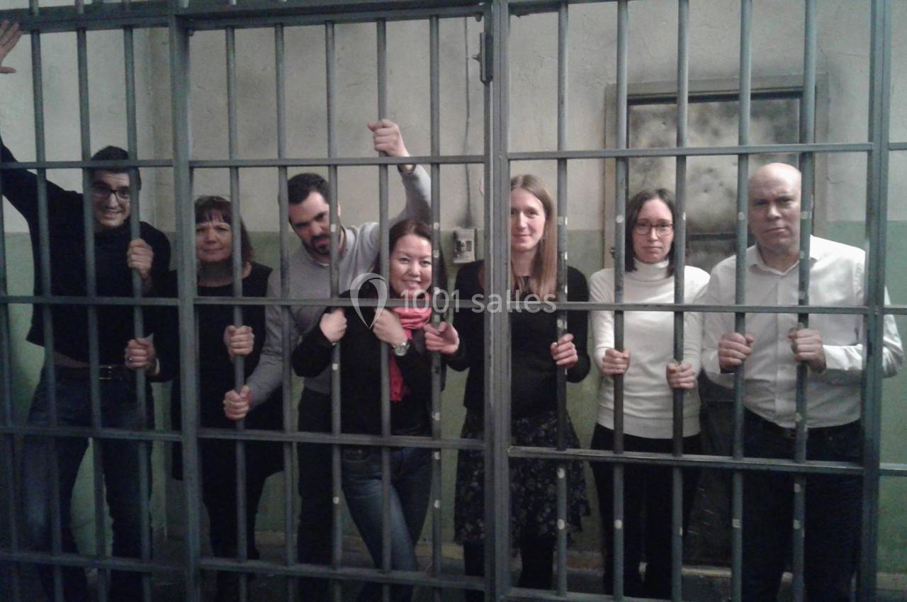 Un groupe de personnes debout derrière des barreaux dans une pièce à l'apparence de cellule.