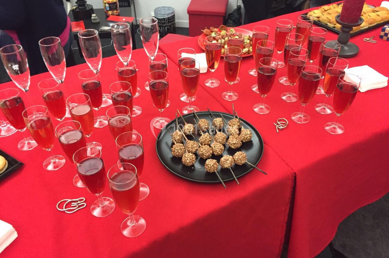 Table rouge dressée avec des verres de cocktail rouge et des brochettes de desserts enrobés de chocolat et noisettes.