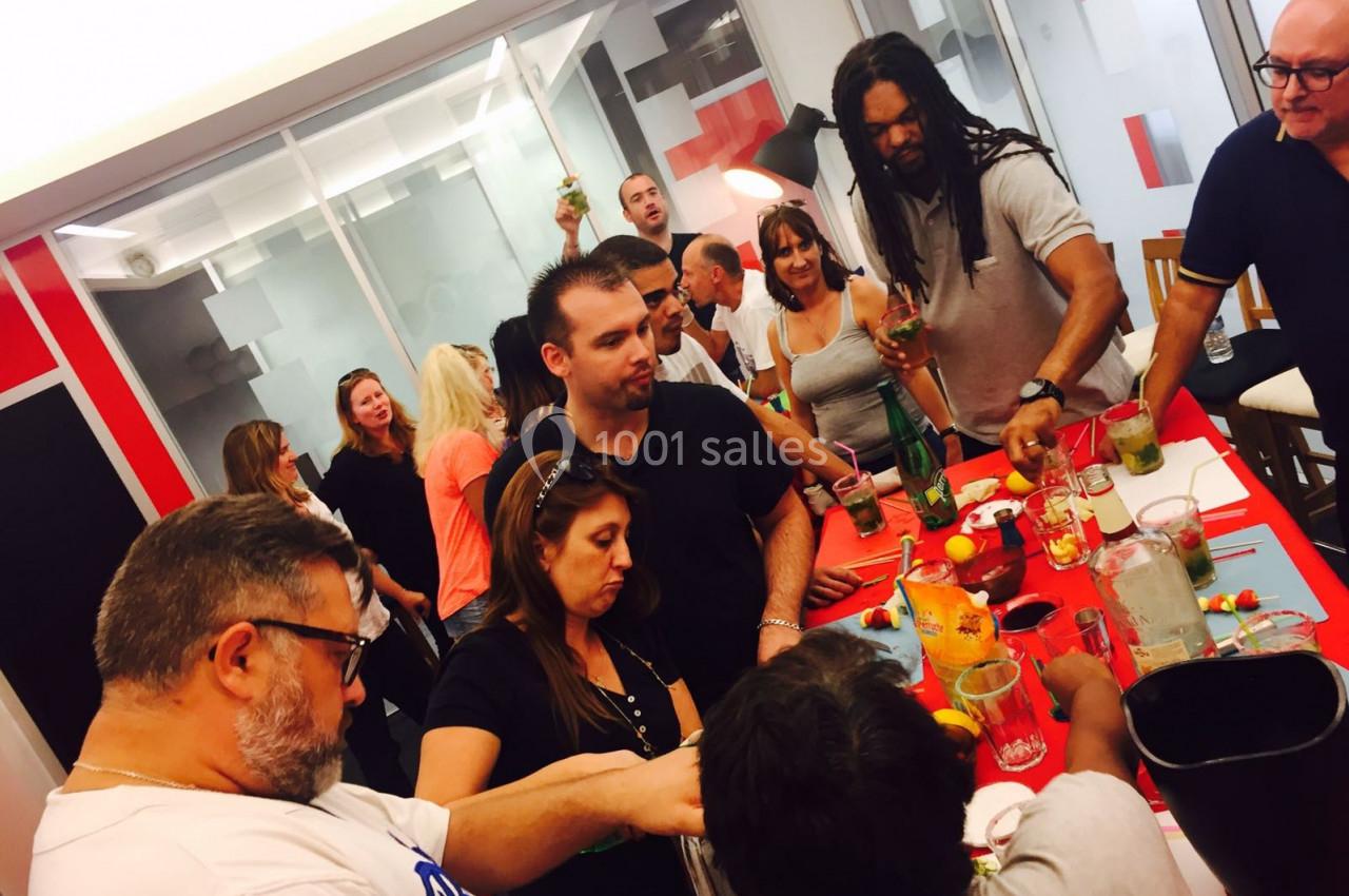 Un groupe de personnes prépare des cocktails autour d'une table dans une ambiance conviviale.